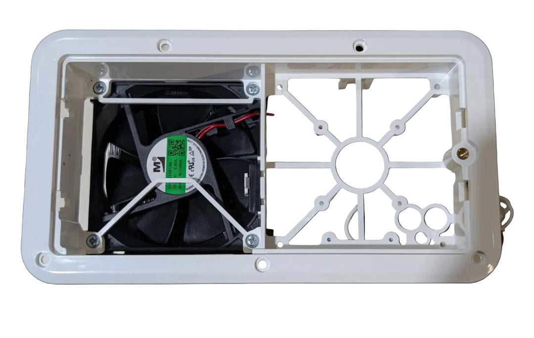 A white plastic rectangular enclosure housing a black cooling fan with a green and white label, mounted against a beige wall.
