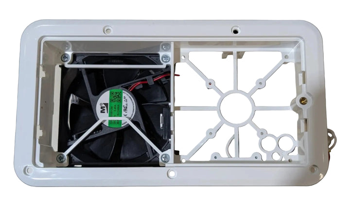 A white plastic rectangular enclosure housing a black cooling fan with a green and white label, mounted against a beige wall.